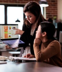 Asian woman living with disability talking to colleague